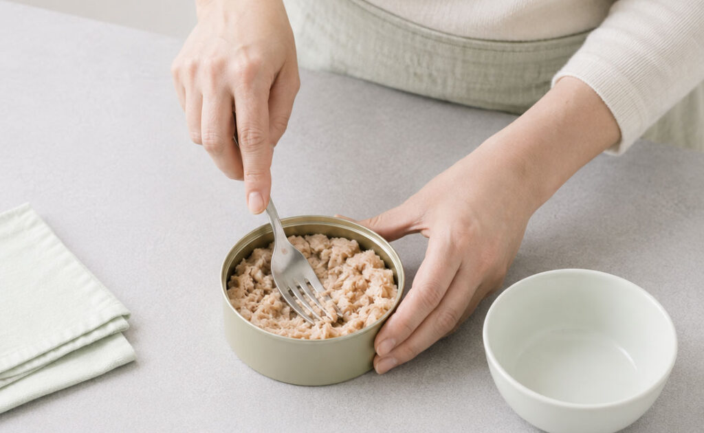 Flaking canned tuna in bowl
