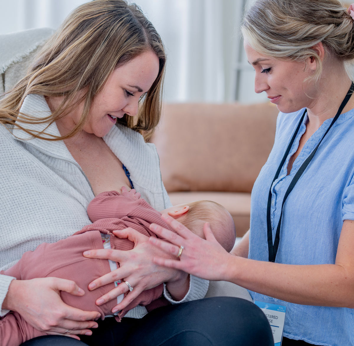 Mother receiving breastfeeding support from a lactation consultant while nursing her baby